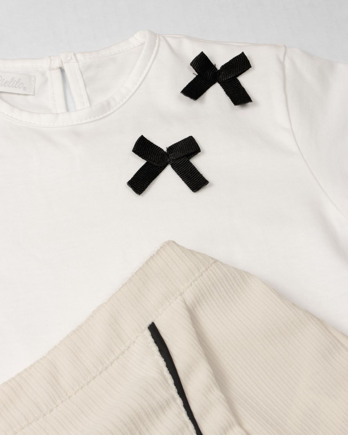 Conjunto camiseta blanca con moños negros y falda short crema para bebé niña