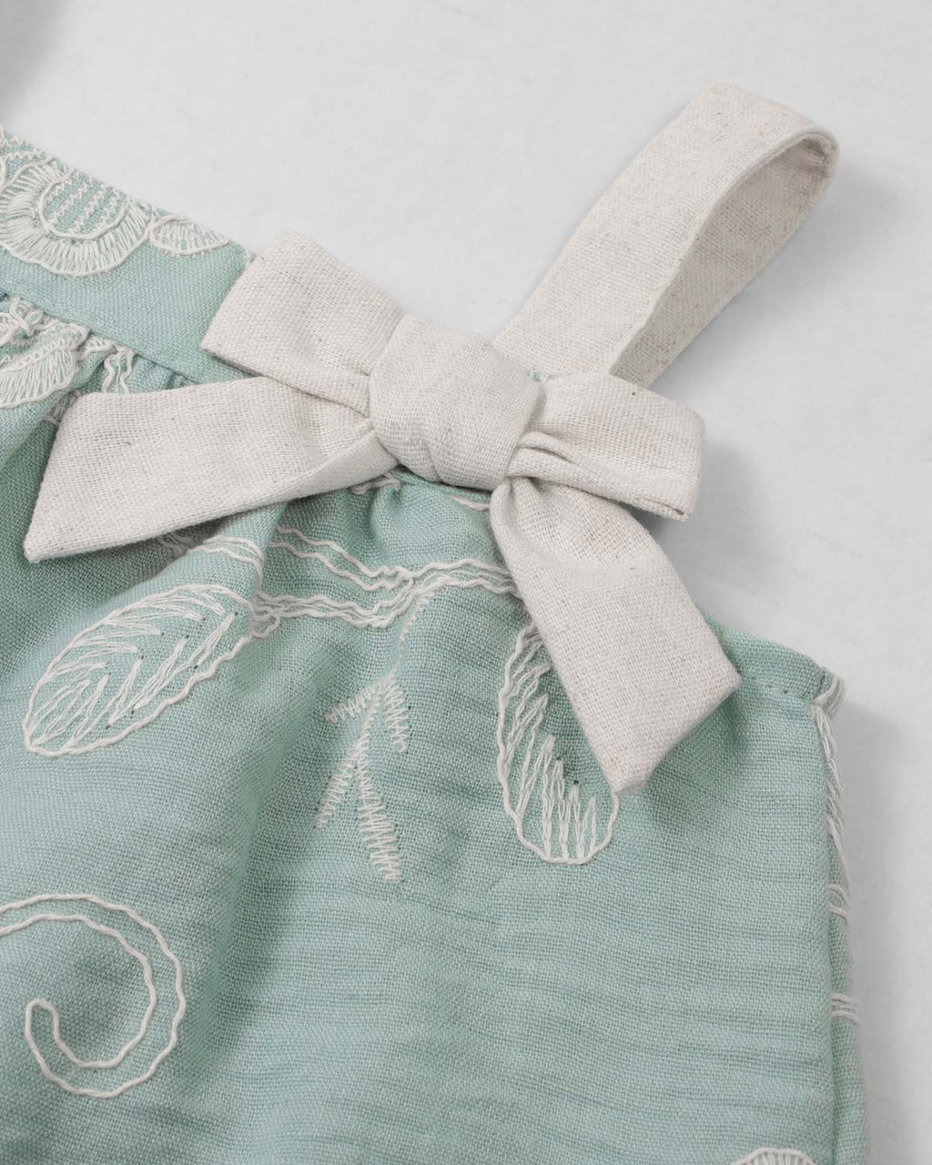 Conjunto blusa verde menta en tela bordada con moño y falda short beige para bebé niña