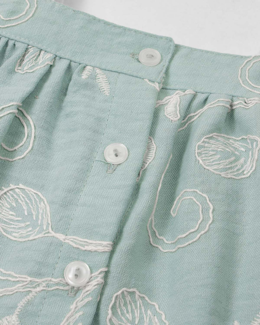 Conjunto blusa verde menta en tela bordada con moño y falda short beige para bebé niña