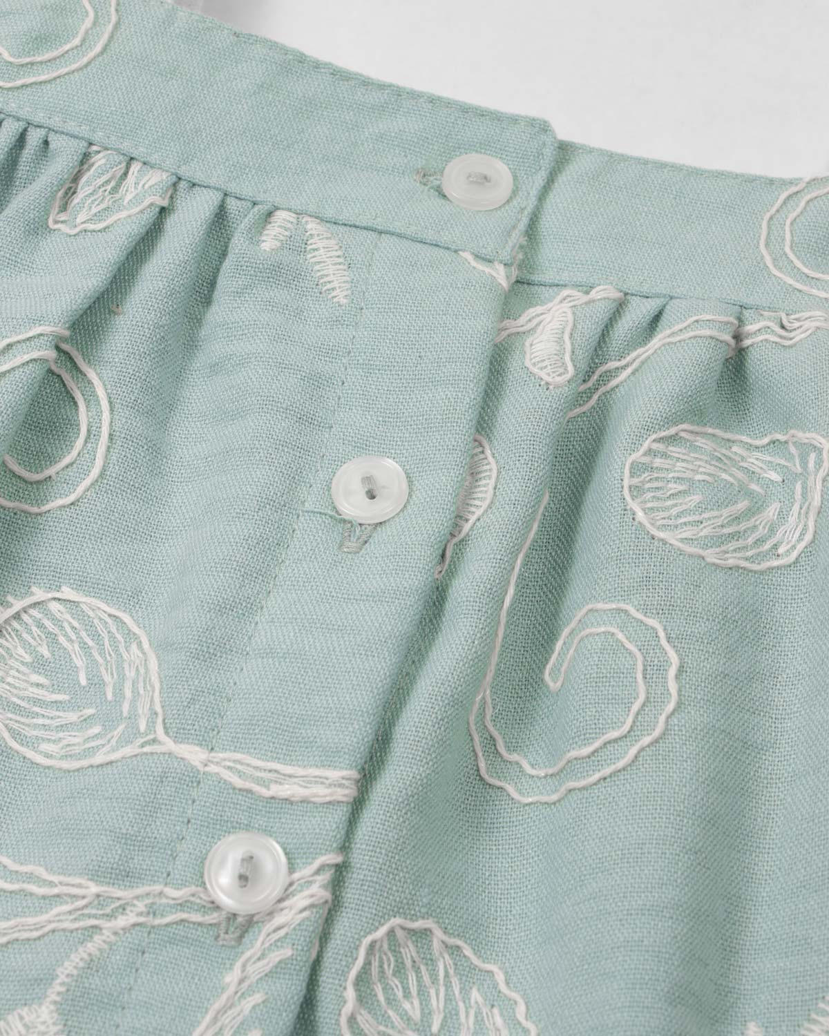 Conjunto blusa verde menta en tela bordada con moño y falda short beige para bebé niña