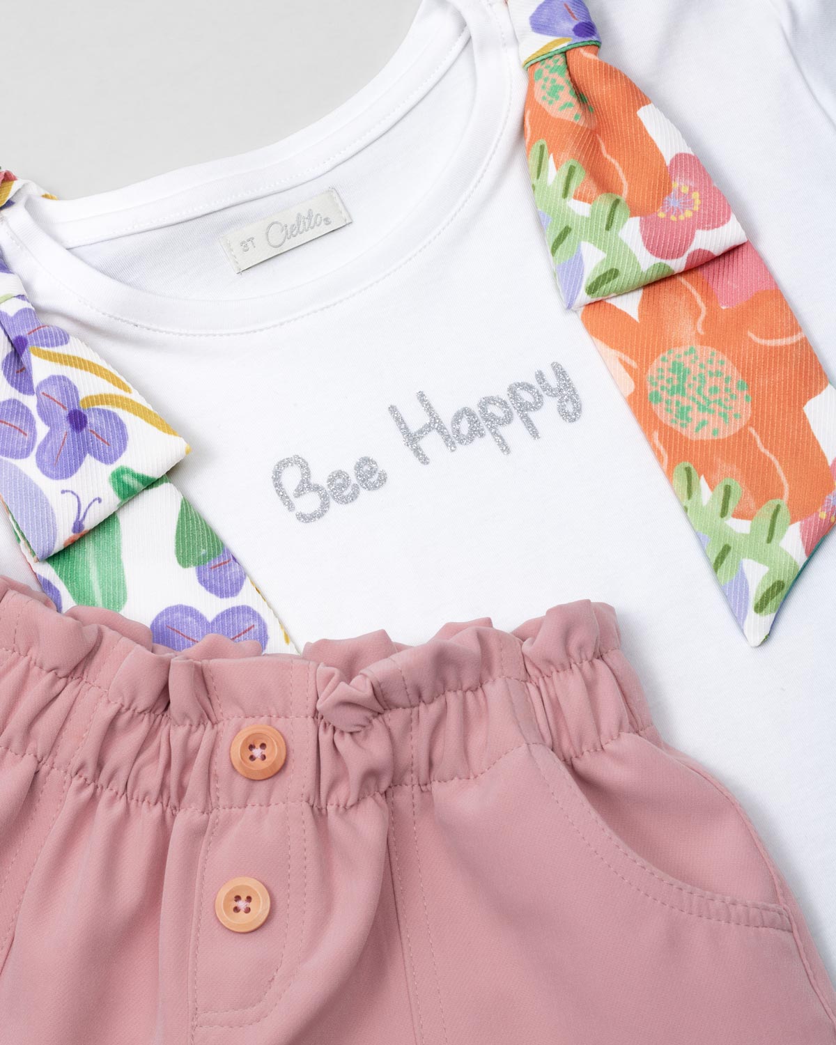 Conjunto blusa blanca con moños estampados en hombro y short rosa con bolsillos para niña