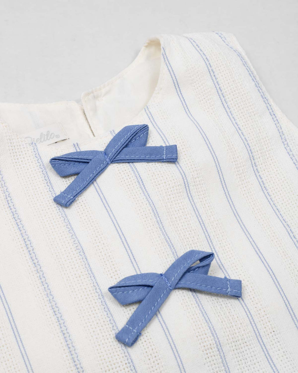 Conjunto blusa blanca con moñitos azules y falda short con prenses azul para niña