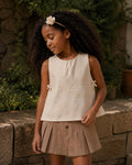 Conjunto blusa en tela hoja rota crema con moñitos y falda short café para niña