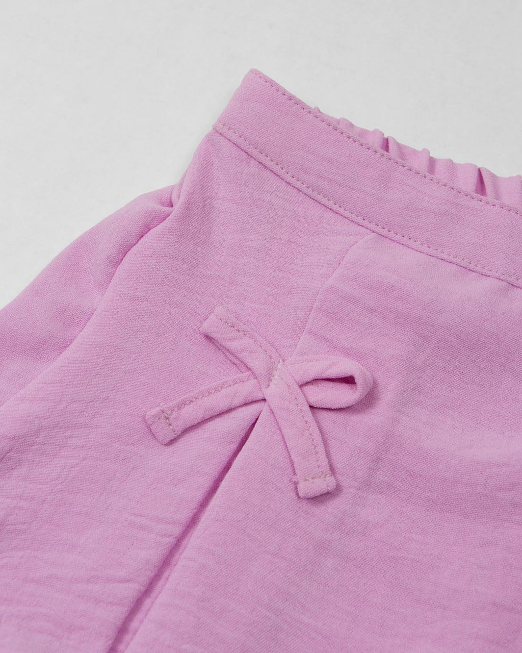 Conjunto camiseta blanca estampada y falda short lila con moños para niña