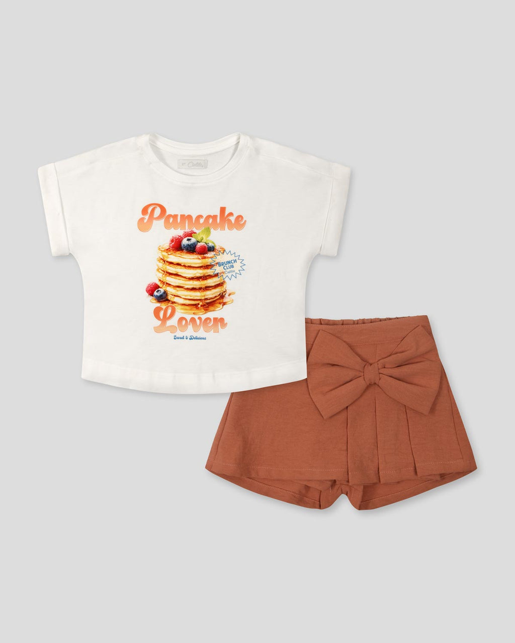 Conjunto blusa blanca con estampado Pancake y falda short con moño para niña