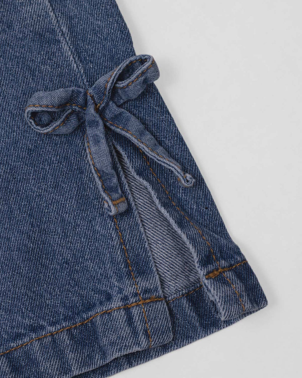 Jean denim marine fit con detalle de moños en la bota para niña