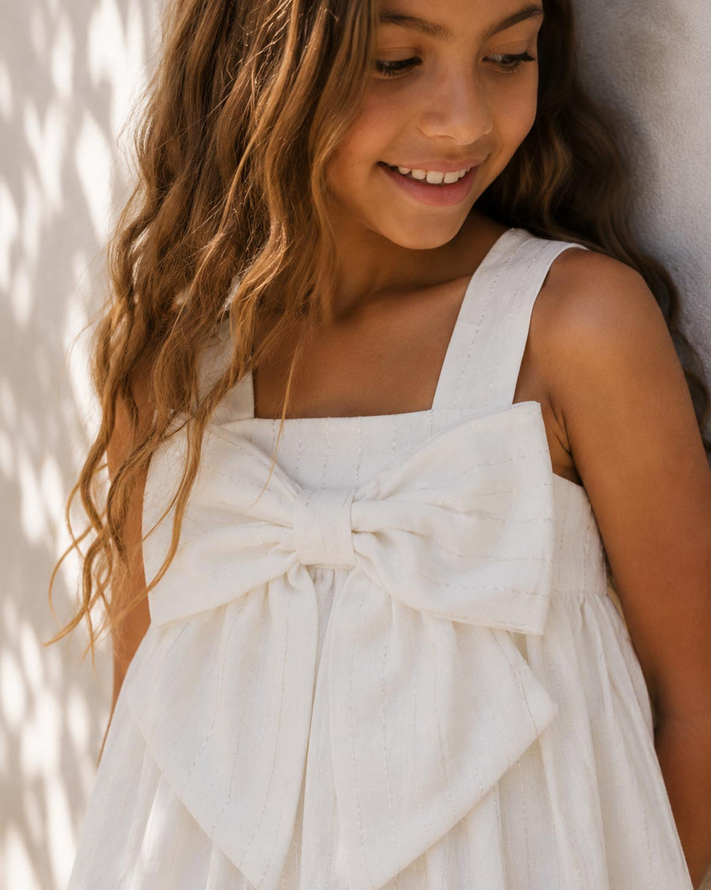 Vestido blanco con moño y líneas con brillos para niña