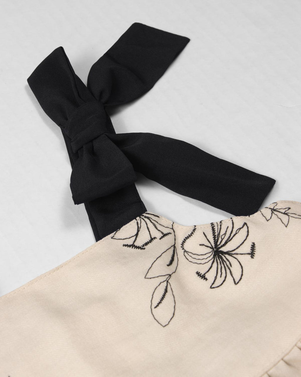 Vestido crema con diseño de flores tejido y tiras con moño para niña